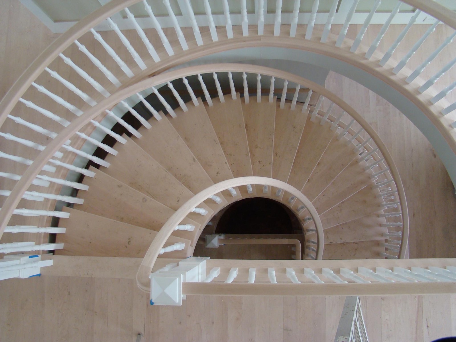 Curved staircase with wood treads and white balusters, seen from above